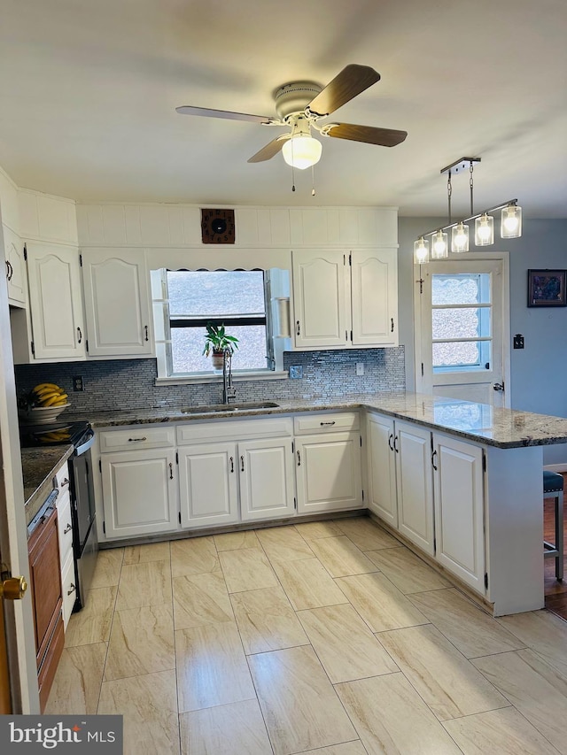 kitchen with white cabinets, pendant lighting, a sink, and a peninsula