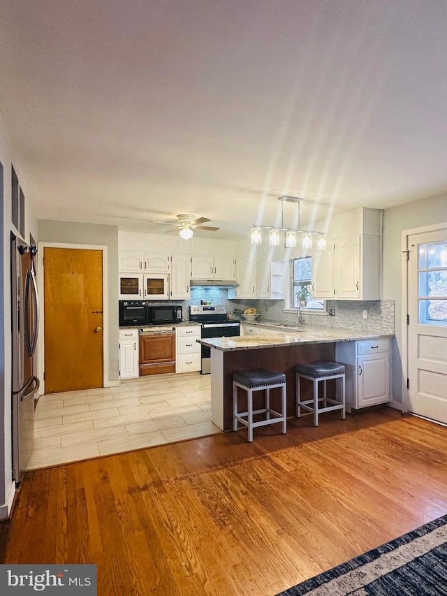 kitchen with a breakfast bar area, light countertops, white cabinetry, stainless steel appliances, and a peninsula