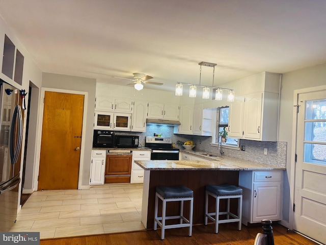 kitchen featuring a sink, white cabinetry, a kitchen breakfast bar, stainless steel appliances, and a peninsula