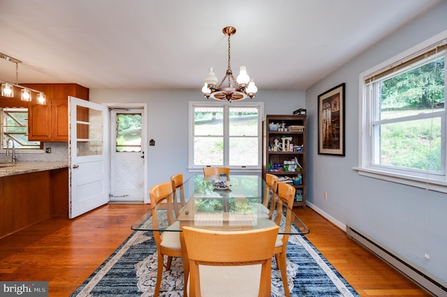 dining space featuring a chandelier, baseboards, a baseboard radiator, and wood finished floors