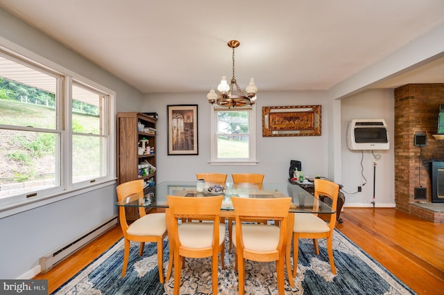 dining room with baseboard heating, wood finished floors, heating unit, a fireplace, and a notable chandelier