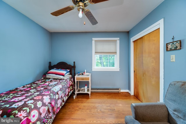 bedroom featuring a baseboard heating unit, a closet, light wood-style floors, and a ceiling fan