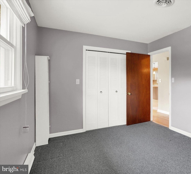 unfurnished bedroom featuring visible vents, baseboards, a closet, and carpet flooring