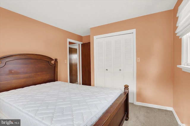 bedroom with light carpet, baseboards, and a closet