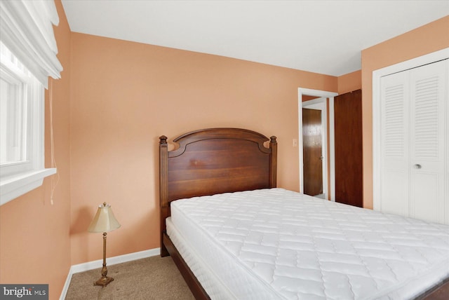 carpeted bedroom featuring a closet and baseboards