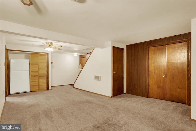 interior space featuring wooden walls, a ceiling fan, and carpet