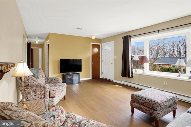 living room featuring visible vents, a baseboard radiator, baseboards, and wood finished floors