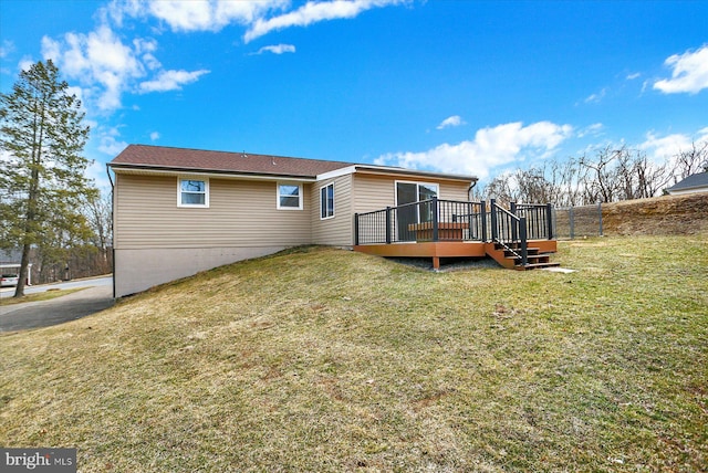 back of property with a wooden deck, a yard, and fence