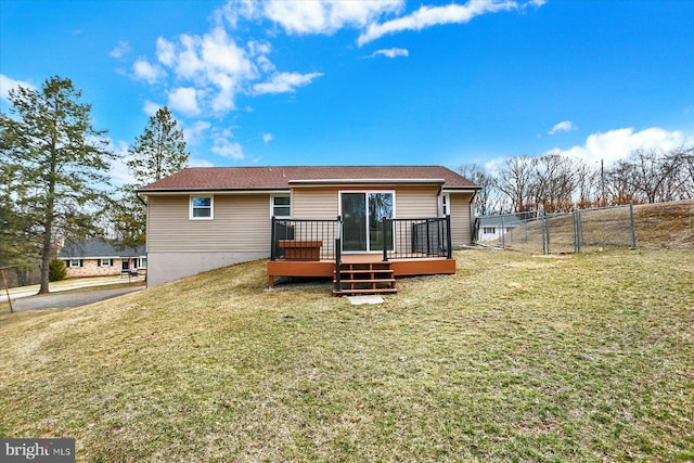 back of house with a gate, a wooden deck, a lawn, and fence