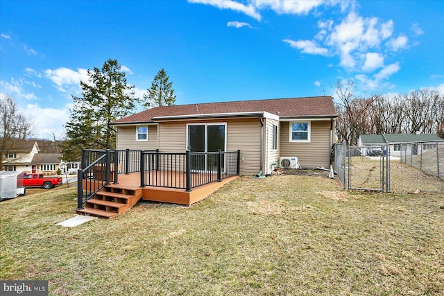 rear view of house featuring a deck, a gate, a lawn, and fence