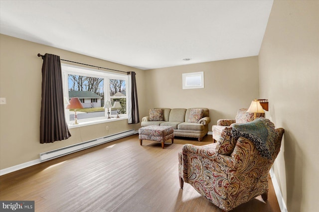 living area with a baseboard heating unit, baseboards, and wood finished floors