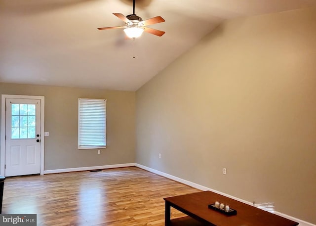 unfurnished living room with light wood-style floors, ceiling fan, baseboards, and vaulted ceiling