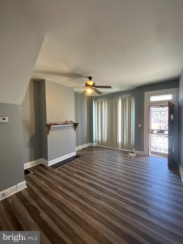 unfurnished living room featuring dark wood finished floors, baseboards, and ceiling fan