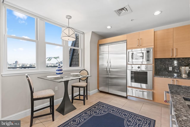 kitchen featuring visible vents, dark stone counters, decorative light fixtures, built in appliances, and a warming drawer