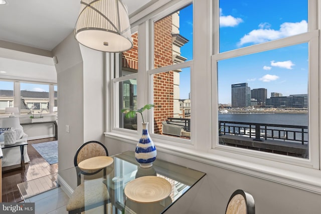 dining space featuring a view of city, a water view, and baseboards