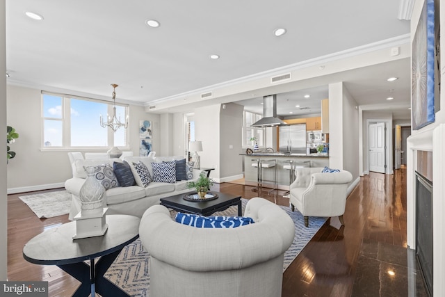 living room featuring dark wood-style flooring, a notable chandelier, crown molding, recessed lighting, and baseboards