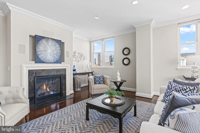 living area with plenty of natural light, wood finished floors, crown molding, and a tile fireplace