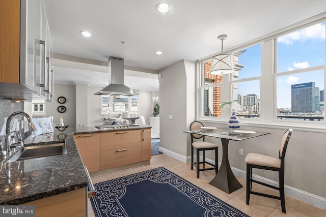 kitchen featuring a view of city, dark stone counters, decorative light fixtures, and island range hood