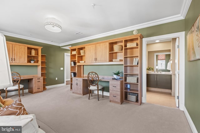 office featuring baseboards, built in desk, light colored carpet, and crown molding