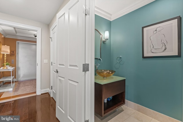 bathroom with ornamental molding, vanity, baseboards, and wood finished floors