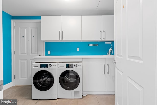 laundry area featuring light tile patterned floors, separate washer and dryer, and cabinet space