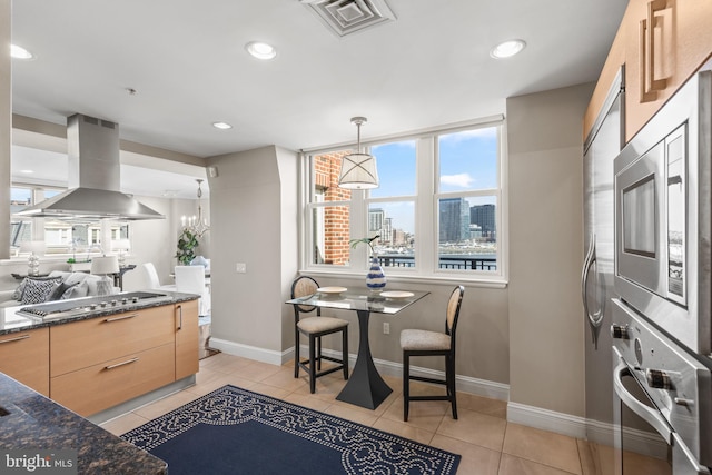 kitchen with light tile patterned floors, light brown cabinets, a city view, appliances with stainless steel finishes, and island exhaust hood