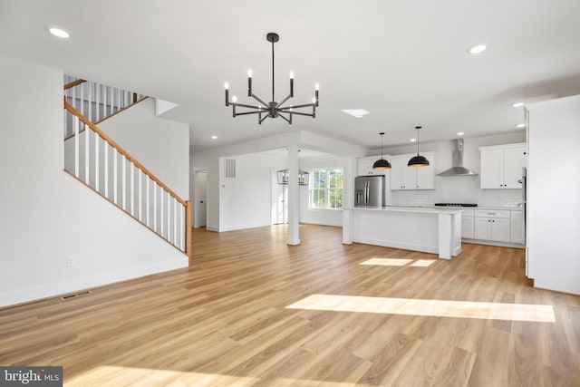 unfurnished living room with an inviting chandelier and light wood-type flooring