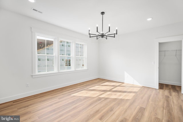 unfurnished dining area with an inviting chandelier and light hardwood / wood-style floors