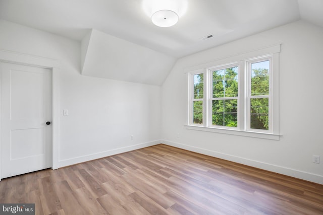 additional living space with lofted ceiling and light hardwood / wood-style flooring