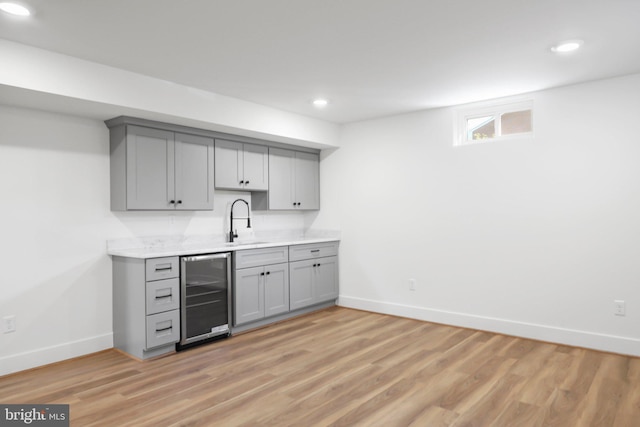 bar with light hardwood / wood-style floors, wine cooler, sink, and gray cabinets