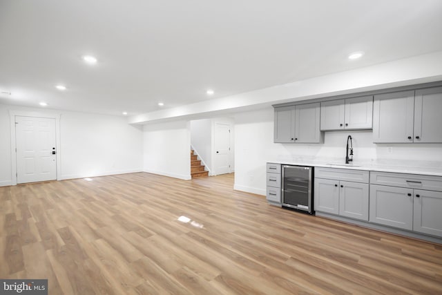 bar featuring gray cabinets, wine cooler, light hardwood / wood-style floors, and sink