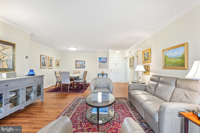 living area featuring baseboards, ornamental molding, and wood finished floors