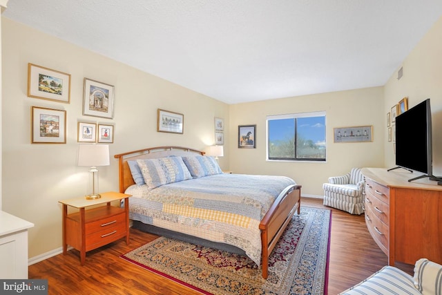 bedroom with dark wood finished floors, visible vents, and baseboards