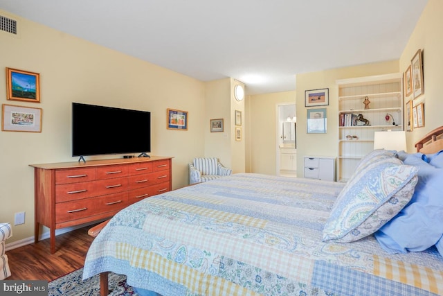 bedroom with dark wood-type flooring, connected bathroom, visible vents, and baseboards