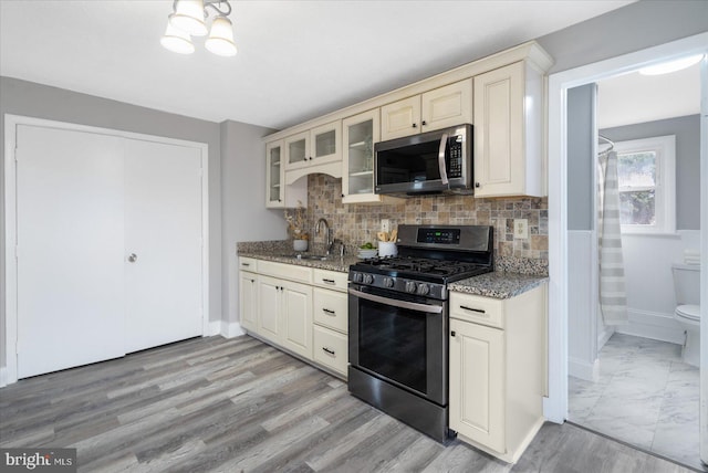 kitchen with stainless steel appliances, dark stone counters, glass insert cabinets, and a sink