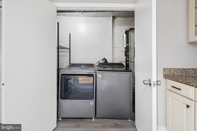 washroom featuring laundry area, wood finished floors, and washing machine and clothes dryer