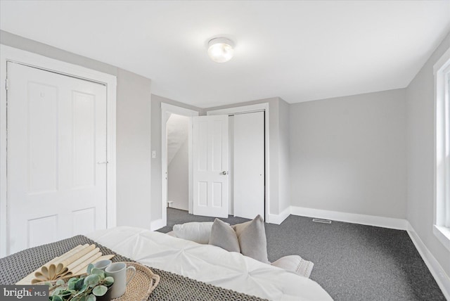 bedroom featuring a closet, dark carpet, visible vents, and baseboards