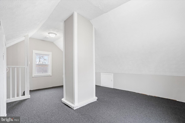 bonus room with lofted ceiling, dark colored carpet, and a textured ceiling