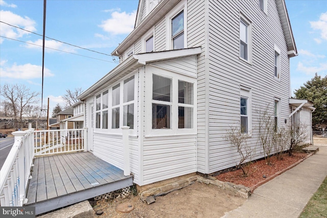 view of property exterior featuring a wooden deck and a sunroom