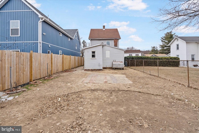 rear view of house with a fenced backyard and heating fuel