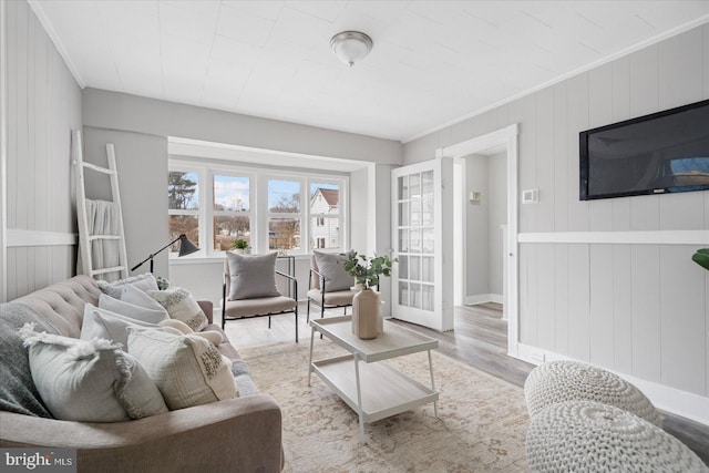 living area with baseboards, light wood finished floors, and crown molding