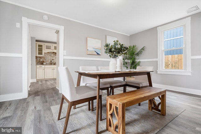 dining area featuring baseboards, crown molding, visible vents, and light wood-style floors