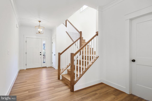 foyer with light wood-type flooring, an inviting chandelier, and ornamental molding