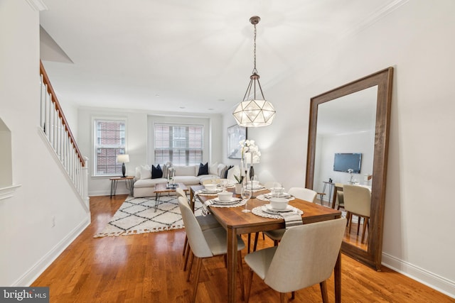 dining space featuring light wood finished floors, stairs, and baseboards