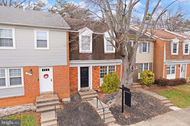 view of property with a shingled roof and brick siding