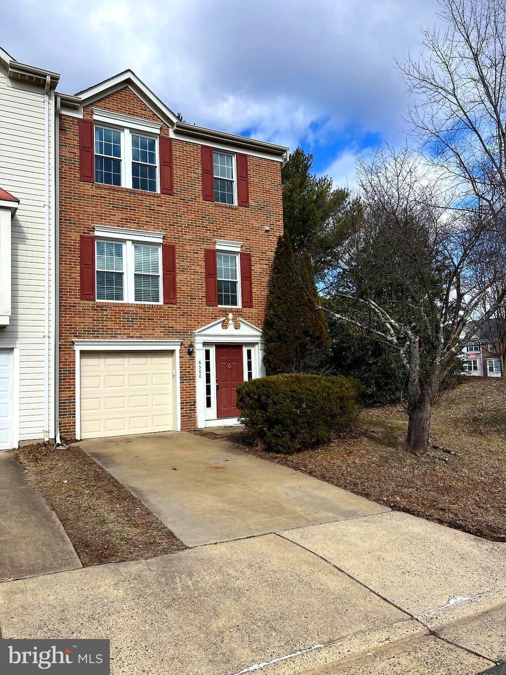 view of front of home with driveway, a garage, and brick siding