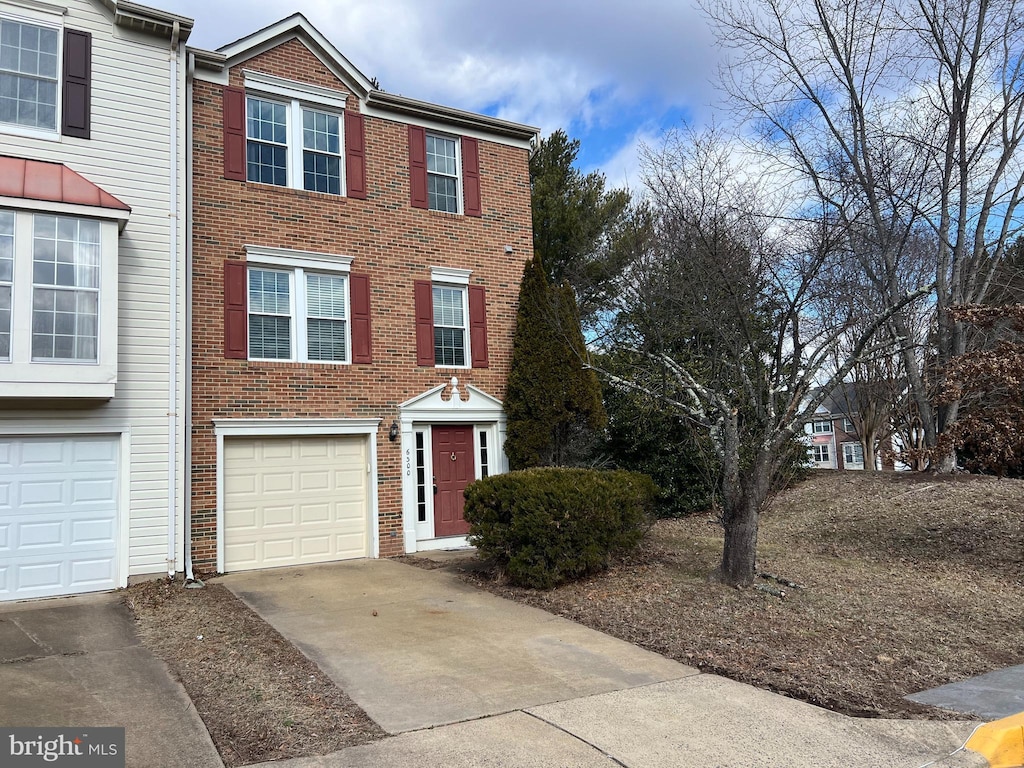 townhome / multi-family property featuring driveway, brick siding, and an attached garage