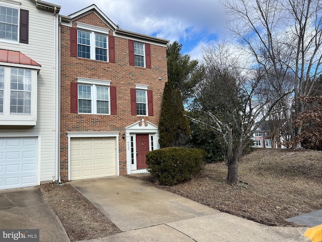 townhome / multi-family property featuring driveway, brick siding, and an attached garage