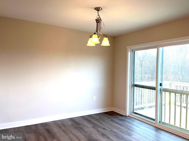 empty room with baseboards, dark wood-type flooring, and an inviting chandelier