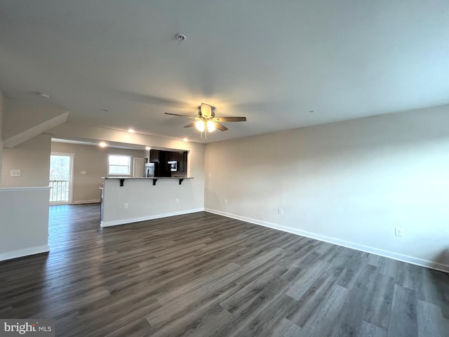 unfurnished living room with baseboards, a ceiling fan, and dark wood finished floors